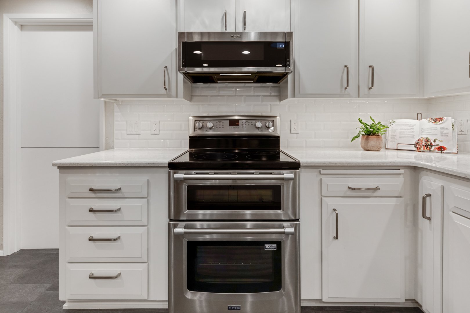 after photo with white countertops and new stainless steel oven/microwave