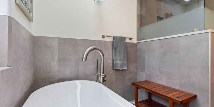 Natural Stone Tile Surrounding White Bathtub.