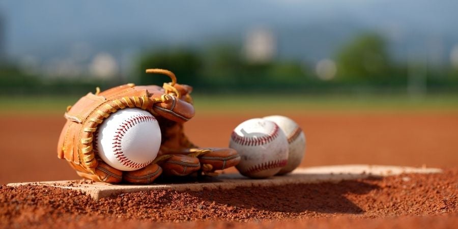 Baseball glove with baseballs resting on baseball diamond