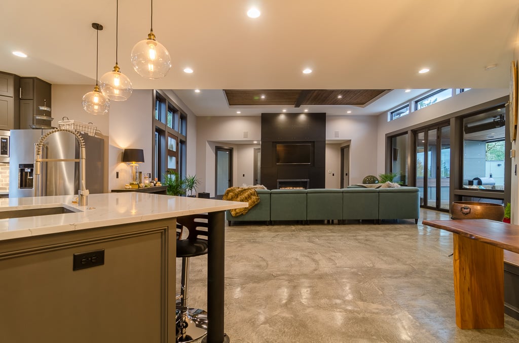 Large open living & dinning room with floor to ceiling black fireplace and green couch