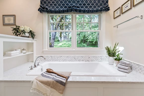 bath tub surrounded with white granite, next to window in remodeled bathrom by Corvallis Custom Kitchens & Baths in Corvallis, Oregon 