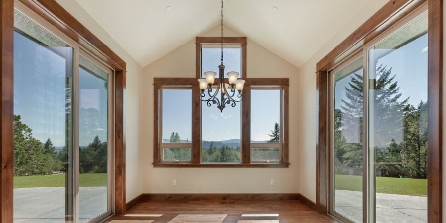 Large Room With Chandelier And Large Windows On Each Wall.