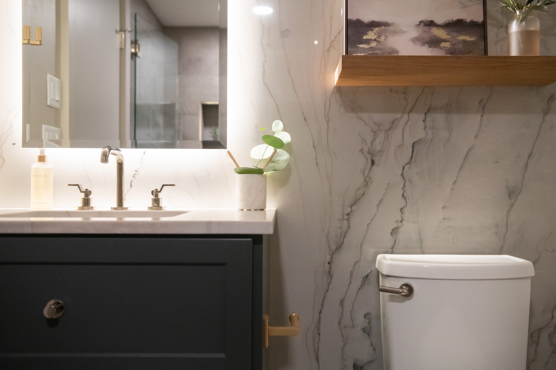 Marbled walls with dark grey vanity and backlit mirror in custom bathroom Marbled walls with dark grey vanity and backlit mirror in custom bathroom