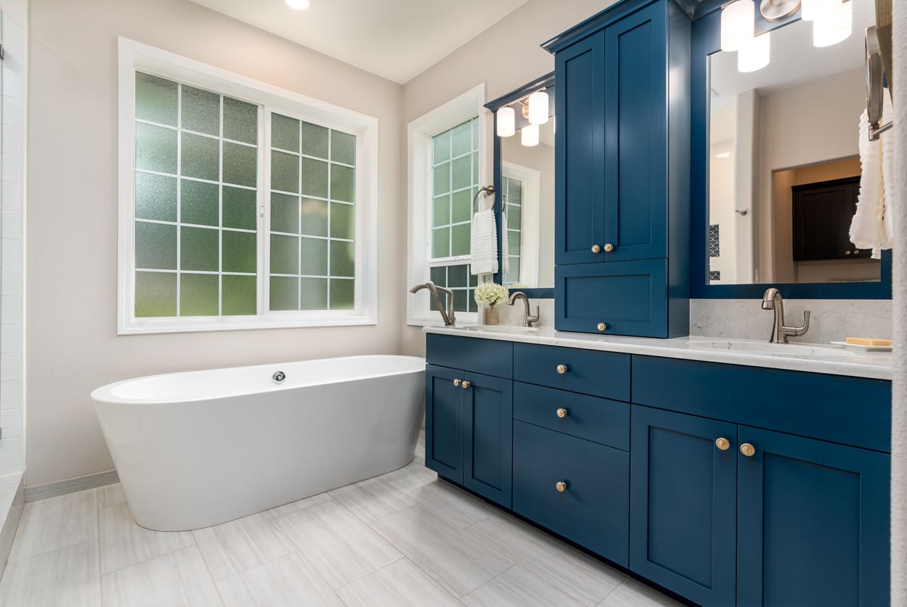 bathroom with light lament floor, blue cabinets, and tub in remodeled bathroom by Corvallis Custom Kitchens and Baths in Corvallis, Oregon