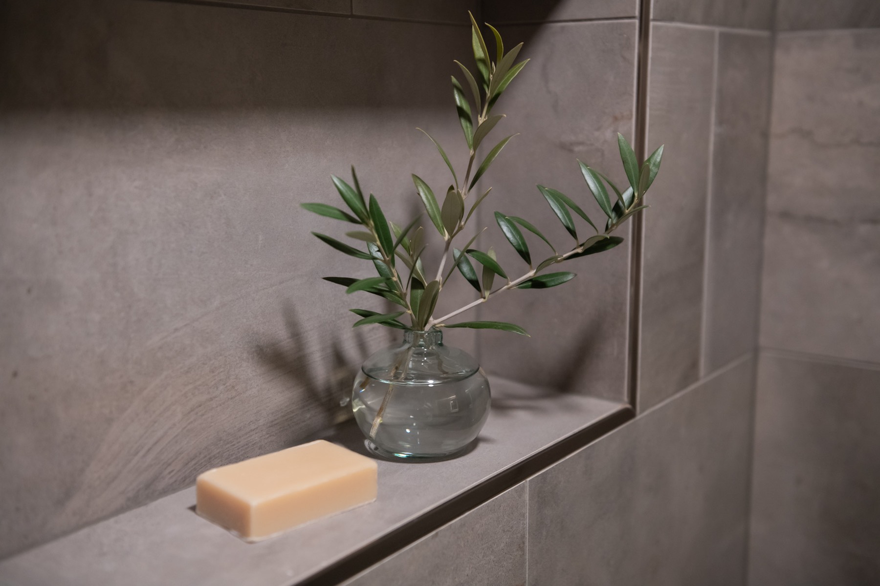 close up of a decorative floral arrangement, vase, and bar of soap sitting inside a beautiful grey shower niche close up of a decorative floral arrangement, vase, and bar of soap sitting inside a beautiful grey shower niche