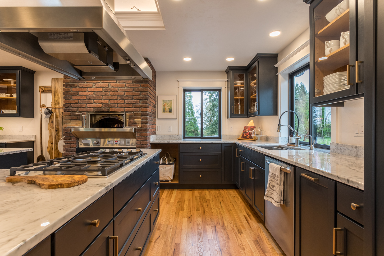custom kitchen addition with black cabinets, brick oven, & gold detail